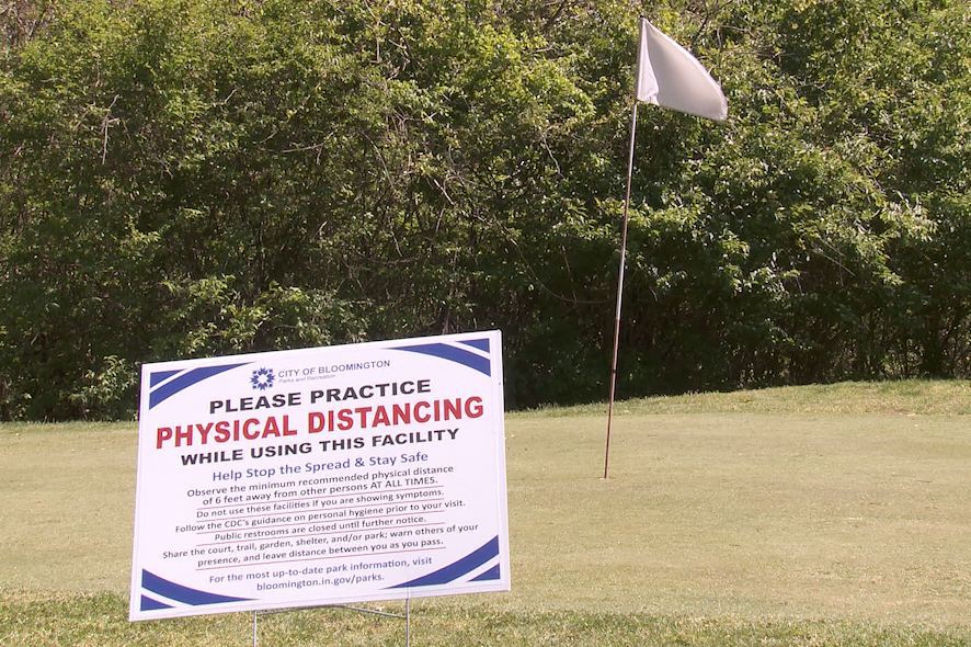A photo of a sign to practice social distancing on the golf course.
