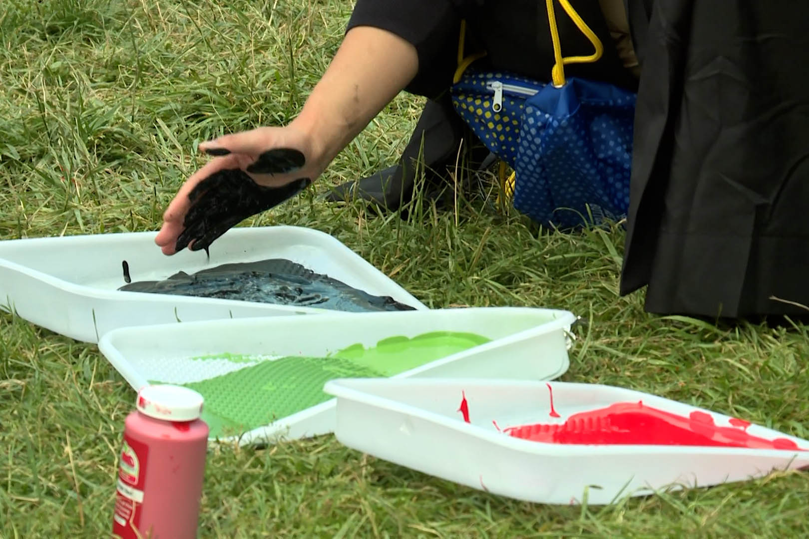 An IU student dips their hand in paint during an alternative commencement ceremony Saturday in Dunn Meadow.