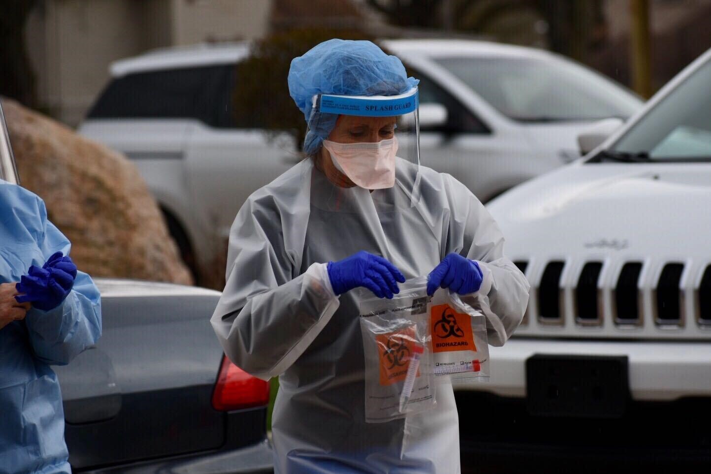 A healthcare worker wearing PPE collects samples for coronavirus testing.
