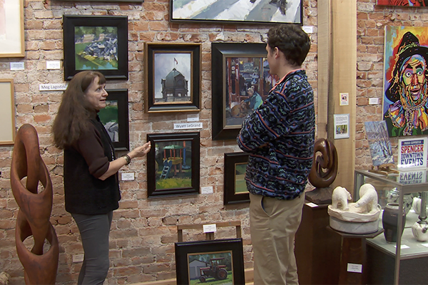 Juniper Art Gallery owner Jaime Sweany shows reporter Mitch Legan some of the artwork in her gallery on the town square