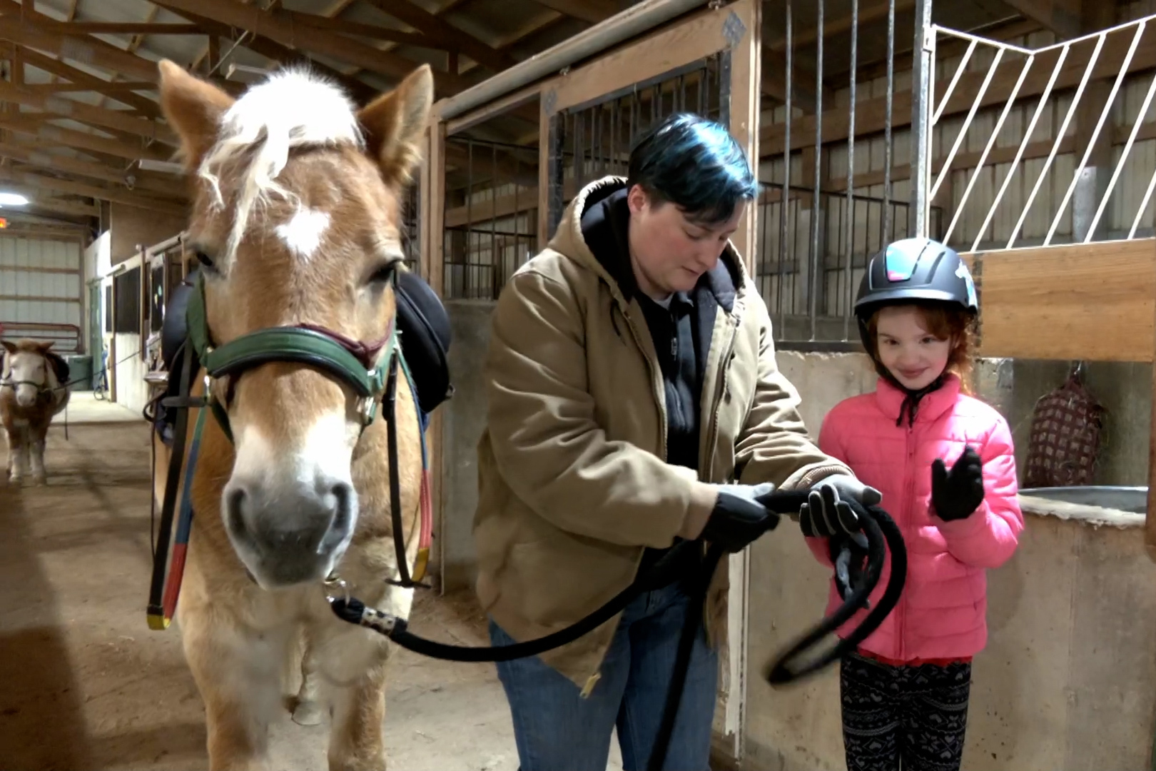 A volunteer helps a young girl with a horse at the PALS Adaptive Riding Center.