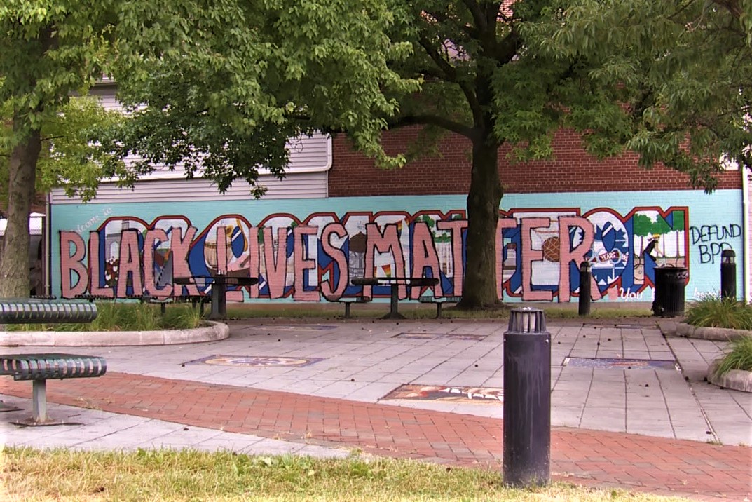The mural at Bloomington's People's Park, painted over with 'Black Lives Matter' and 'Defund BPD.'