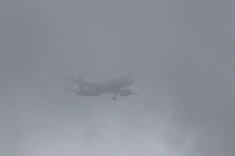 A plane flies in foggy/fog conditions.