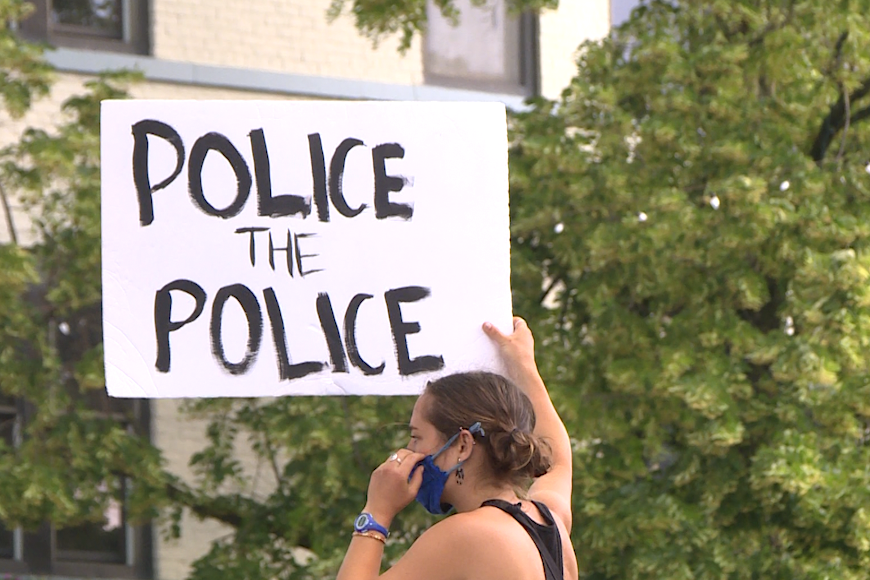 A protester holding up a sign that says "Police the Police."