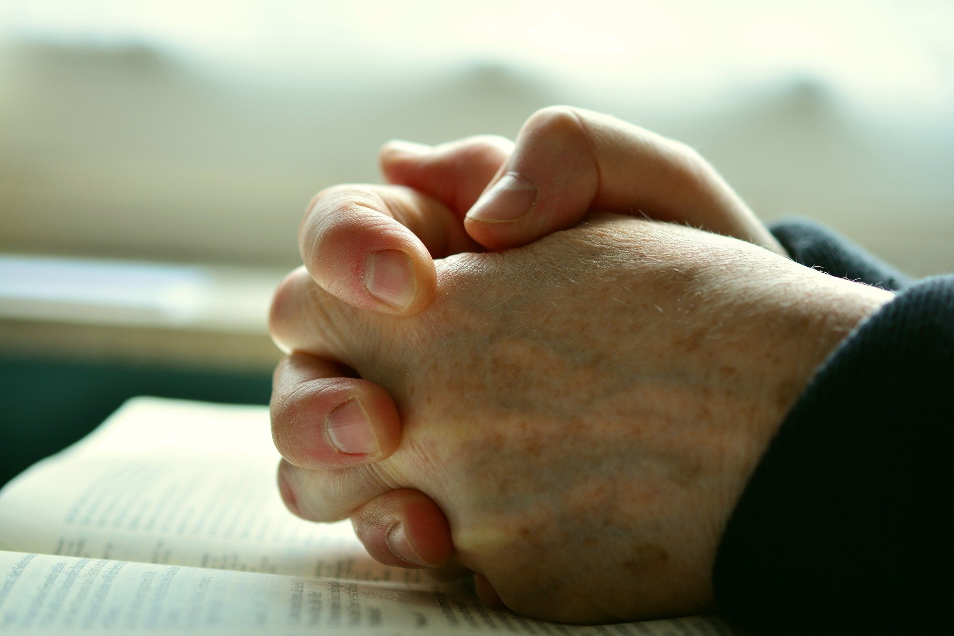 A stock image of a man's hands clasped in prayer/praying.