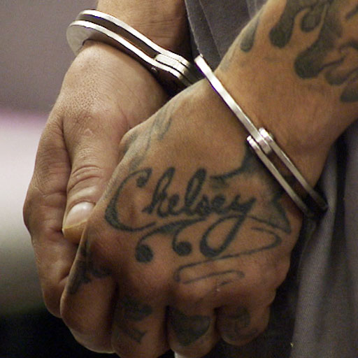 someone in handcuffs. a tattoo on the left hand reads "Chelsey"