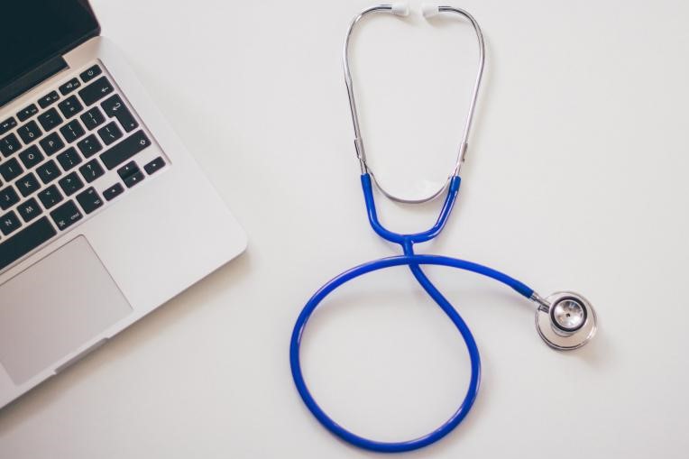 A stock image of a stethoscope and laptop.