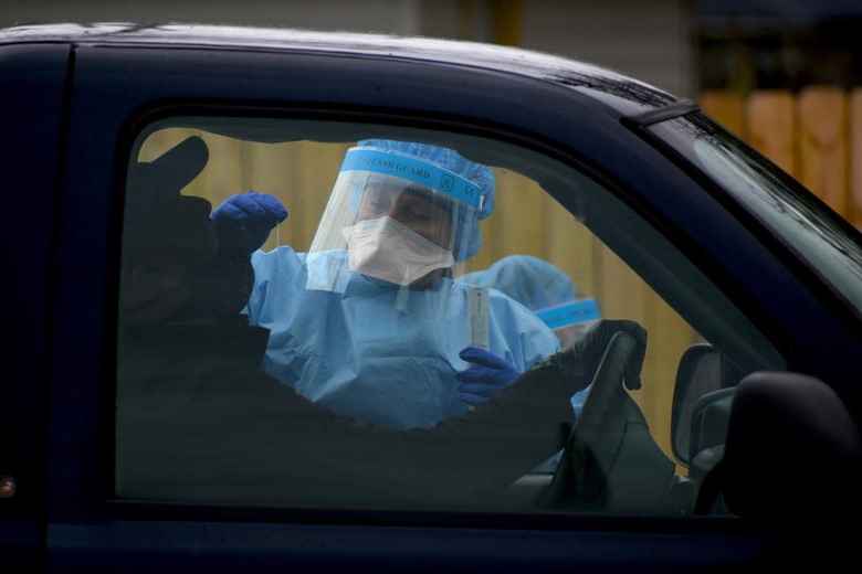 A healthcare worker speaks with someone in a coronavirus drive thru testing facility in Bloomington.