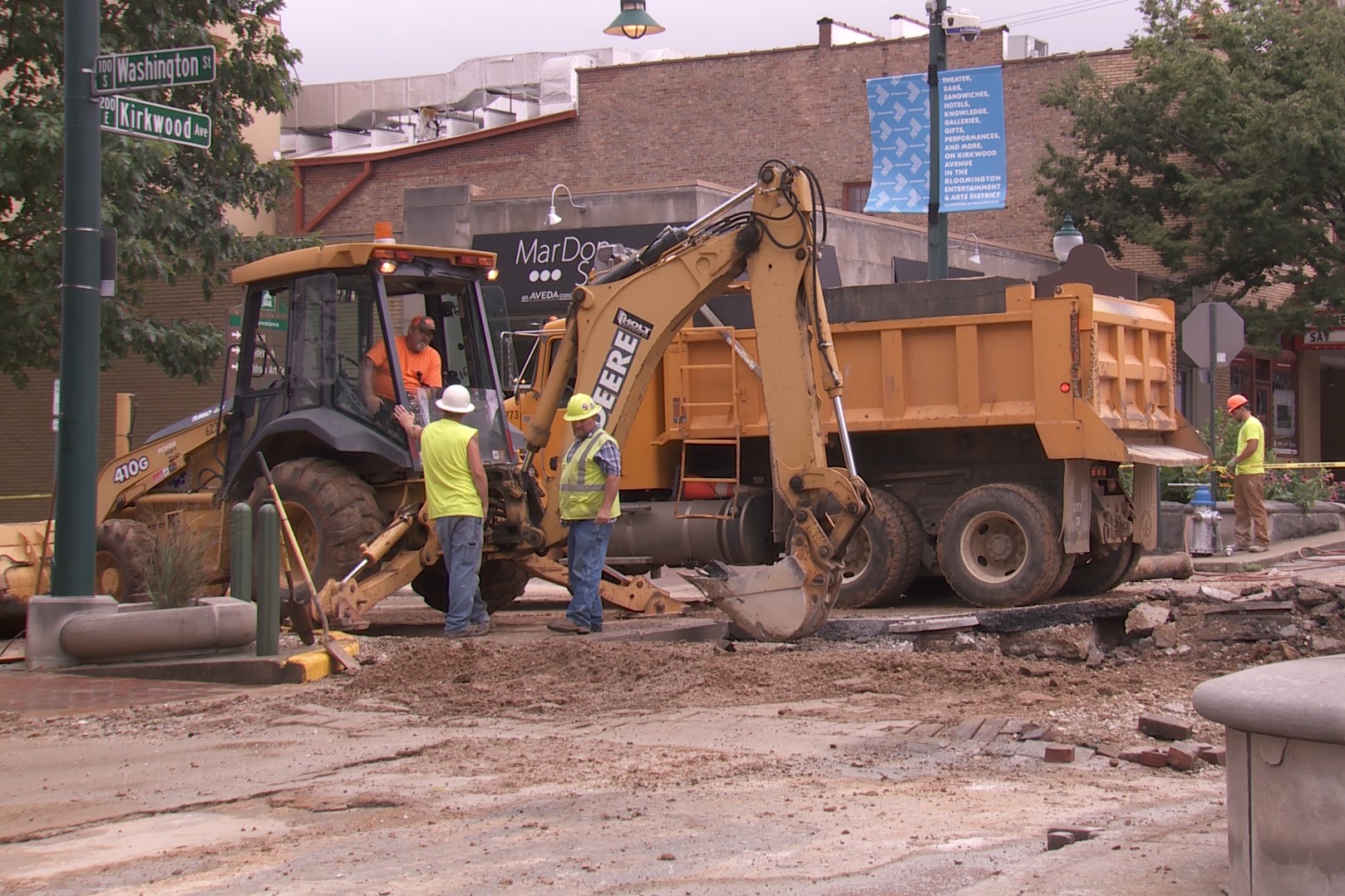 Construction workers operate a large digging mchine while fixing a water main break at the intersection of Washington and Kirkwood. July 2019.