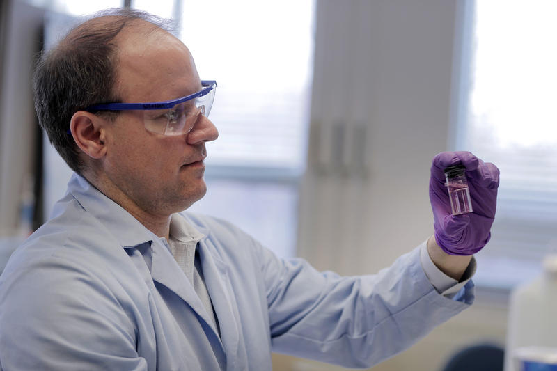 Purdue University professor Andrew Whelton looks at water sample from a faucet. The pink color shows that the sample may contain chlorine — a disinfectant used by utilities to kill bacteria.