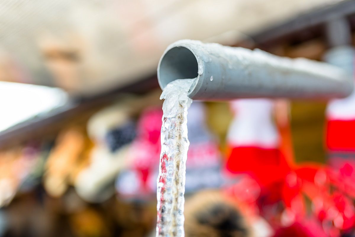 Frozen water flowing from the roof through a plastic pipe with a string inside