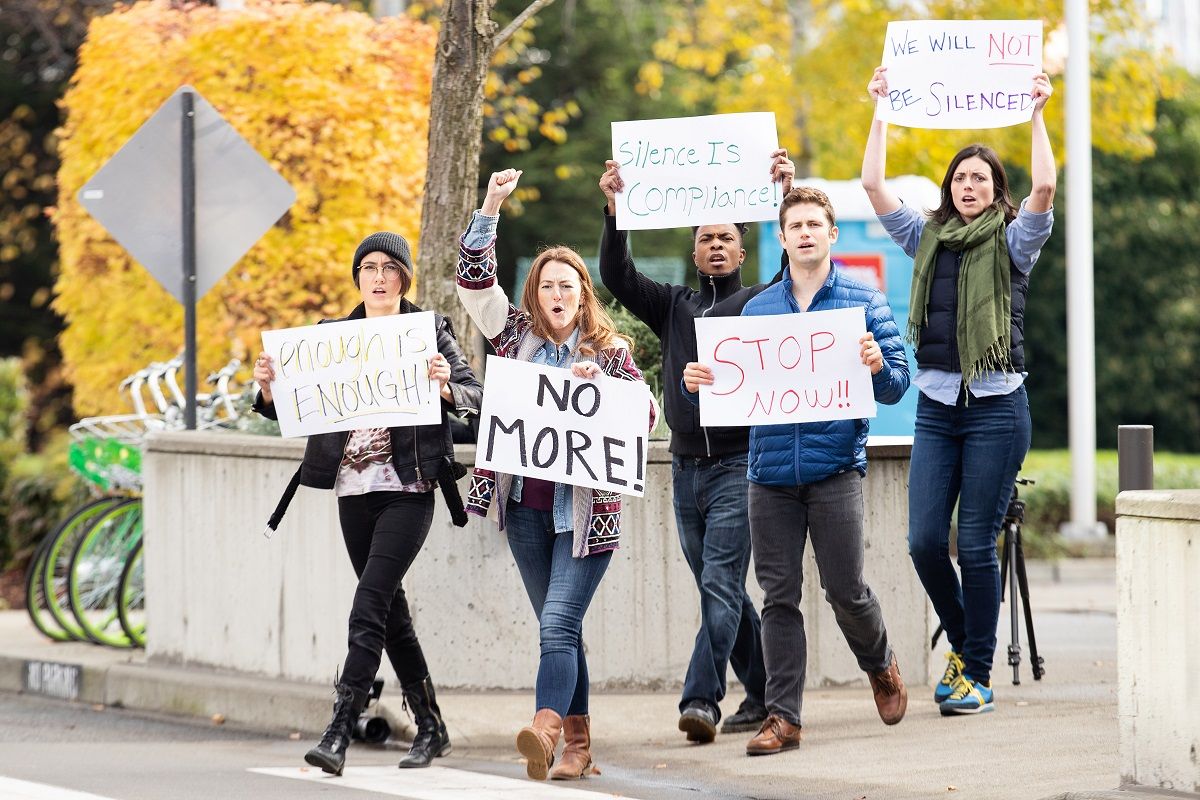 Group of five people protesting outside with signs