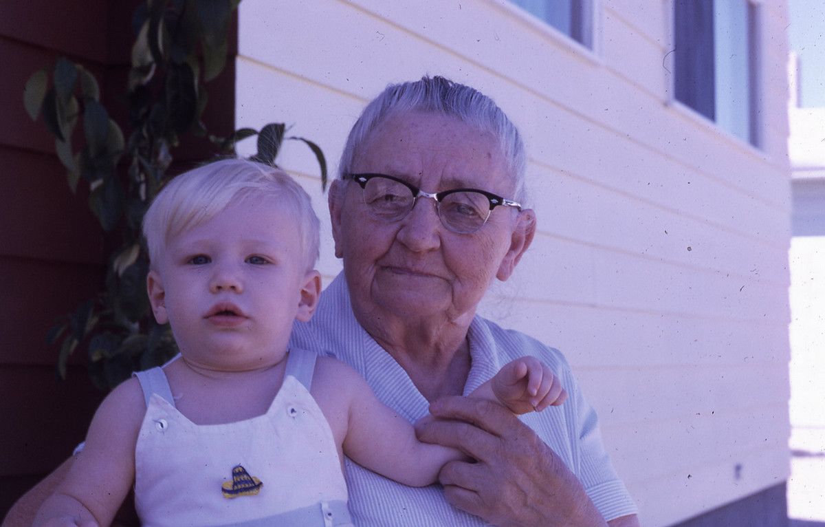 A photo from 1967 of an older woman holding her grandchild, both looking at the camera