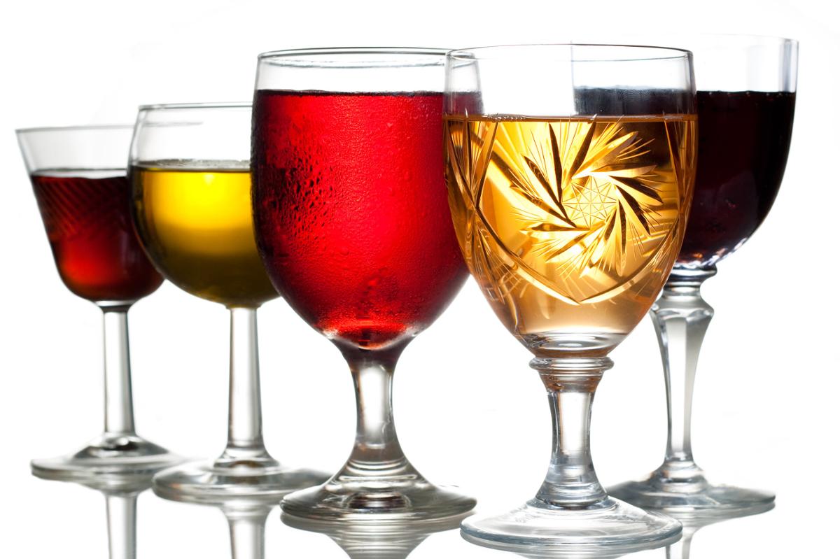 A collection of various shaped glasses of alcohol against a white background
