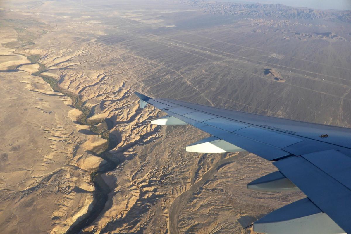 A view of the Atacama Desert in Chile taken from above, with a plane wing in the bottom corner