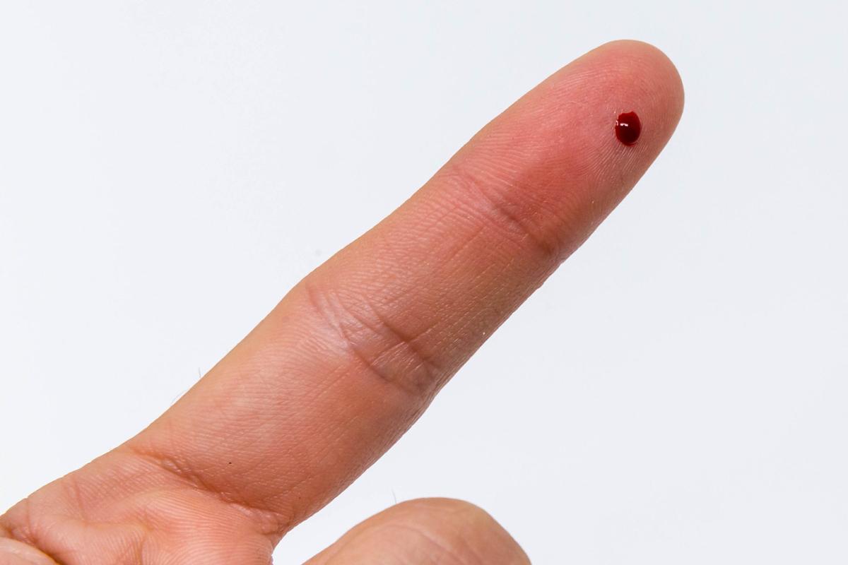 A drop of blood on a person's extended finger after being pricked