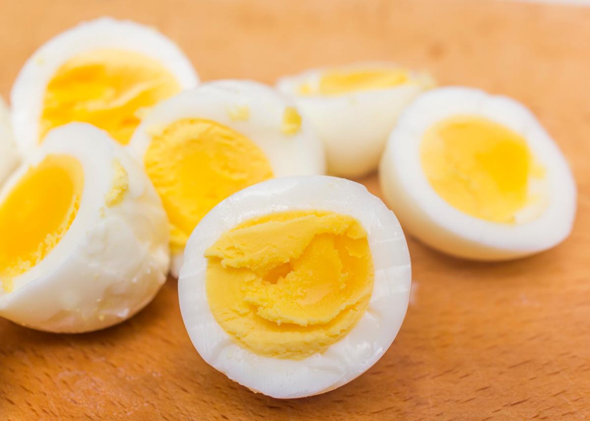 Several hard boiled eggs cut in half sit on a wooden surface