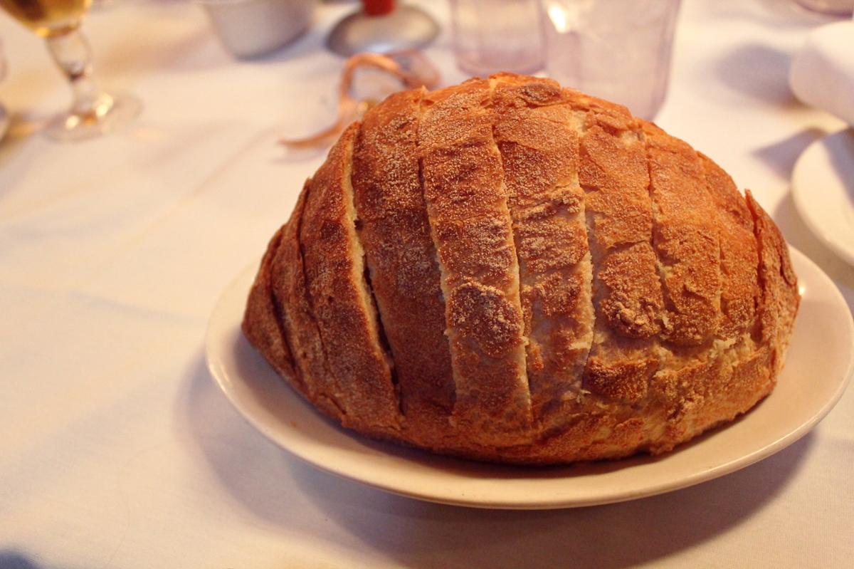 A round loaf of homemade bread sits on a plate on a white countertop