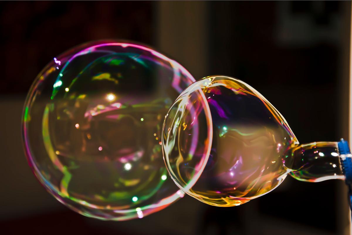 Several large bubbles just being formed, with multiple colors reflected off their surface