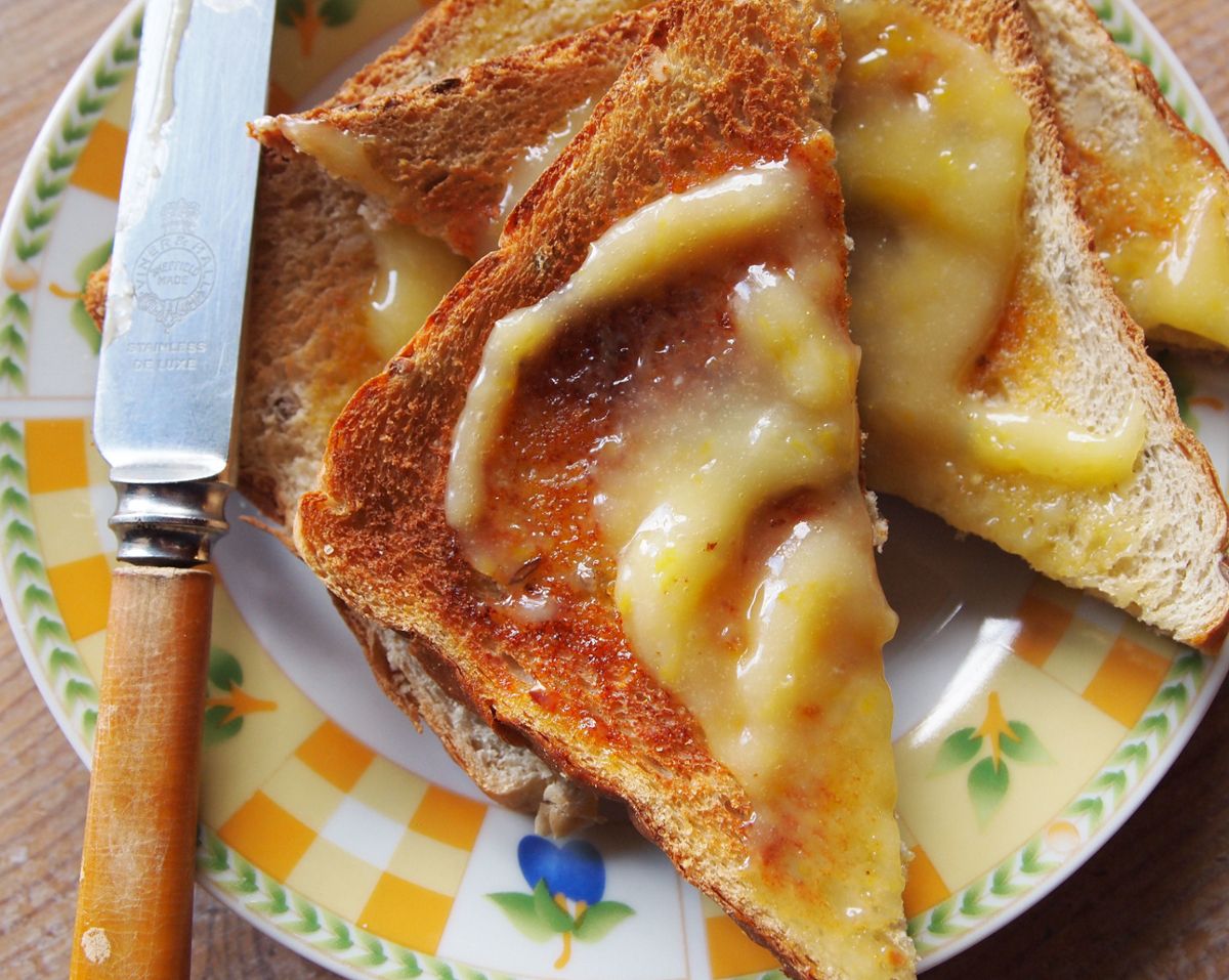Toast with plenty of butter on a colorful plate, with a knife nearby