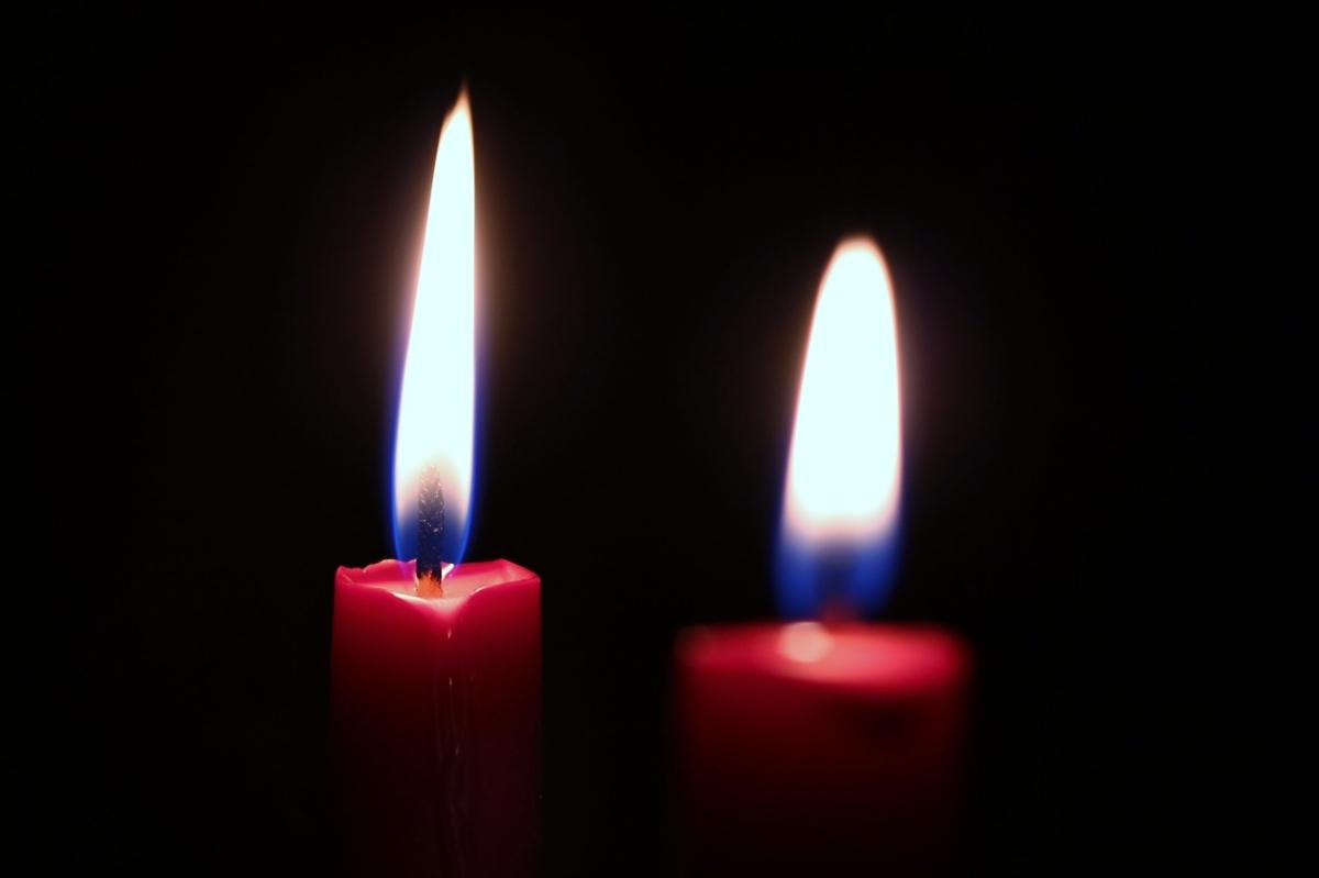 Two lit red candles against a dark background