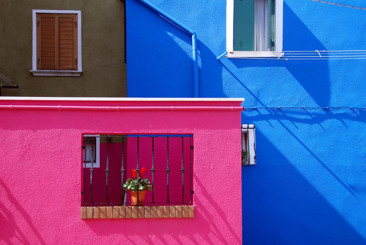 Two brightly painted walls of houses connecting, one pink one blue