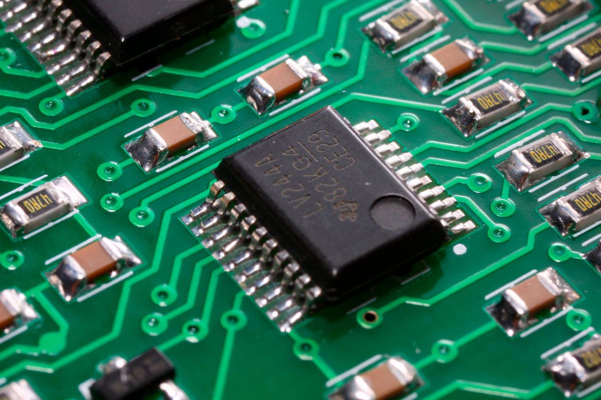 A computer chip in closeup on a green circuit board