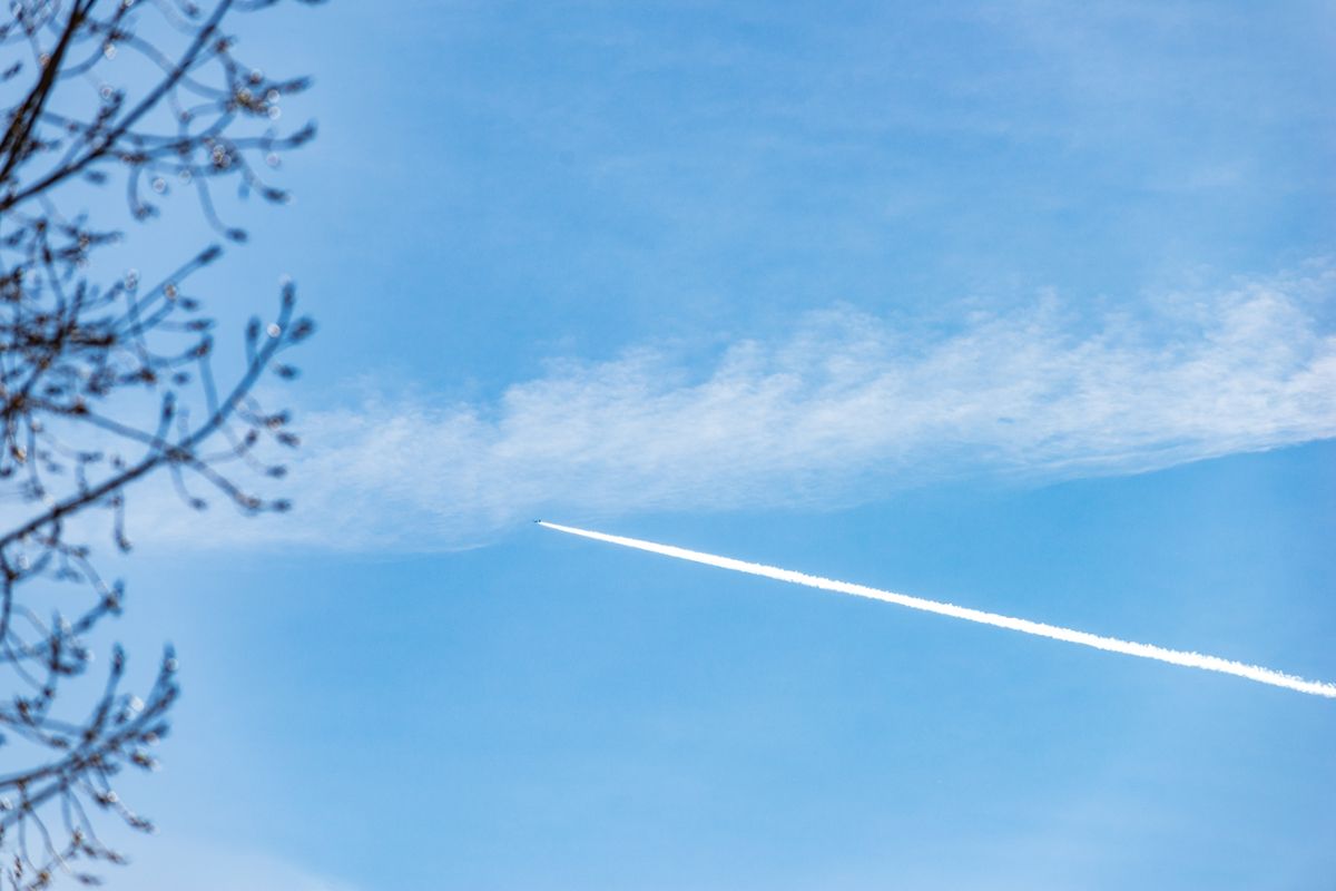 A plane flying in a blue sky, with white contrails behind it