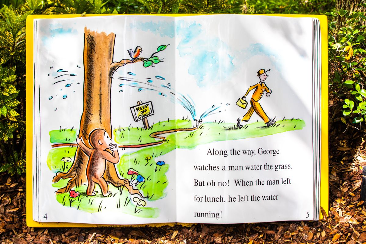 A page from a Curious George book, as George watches a man watering the grass walk away