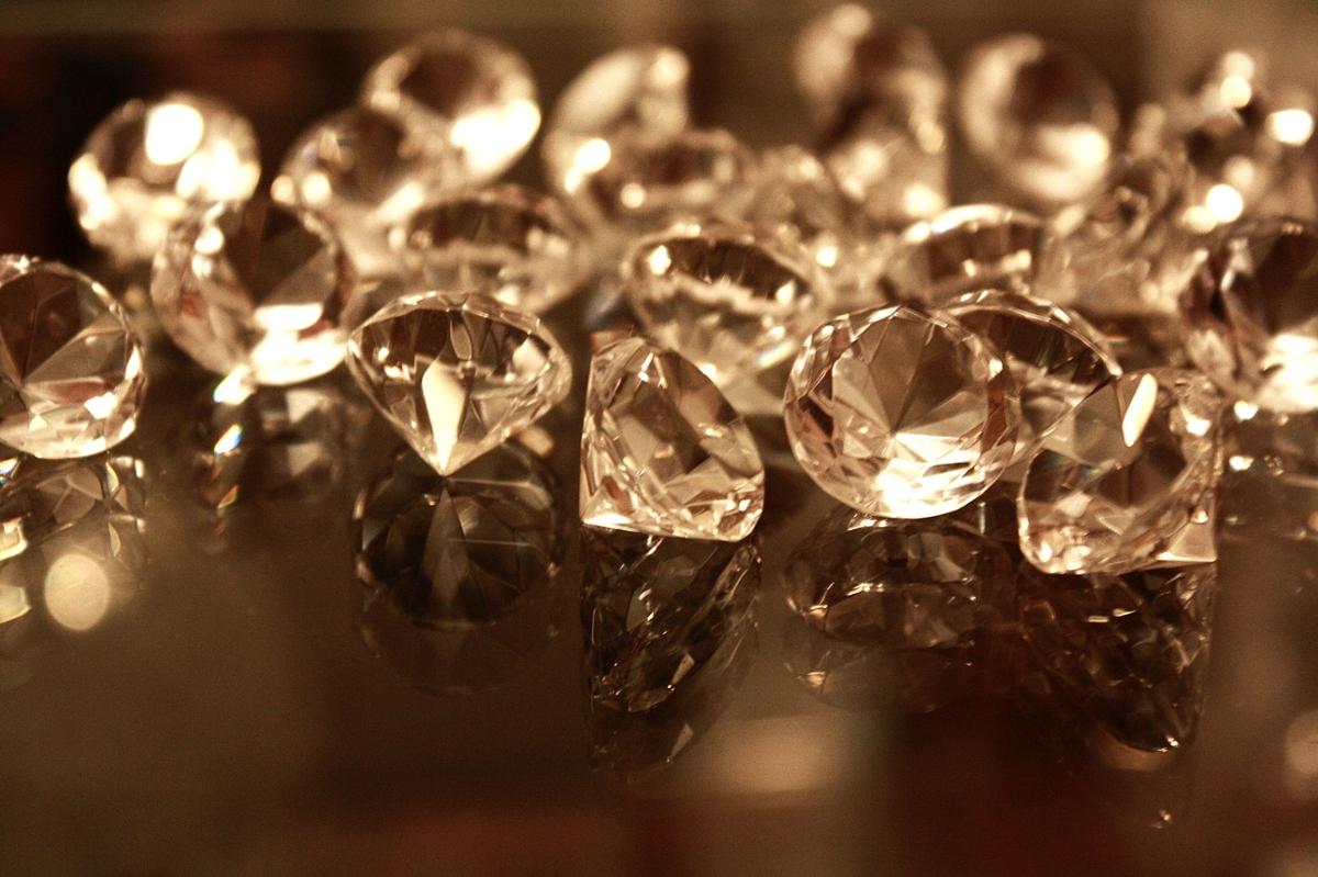 Several clear diamond crystals sit on a glass surface in a sepia-toned photo
