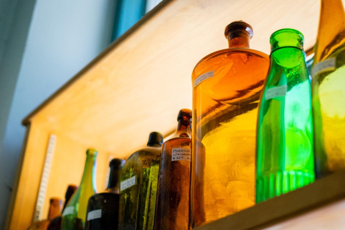 A shelf with antique glass bottles of varying size and color