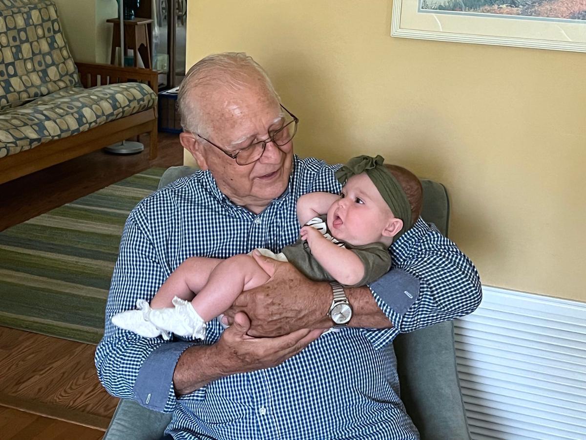 An older man holds a baby in his arms