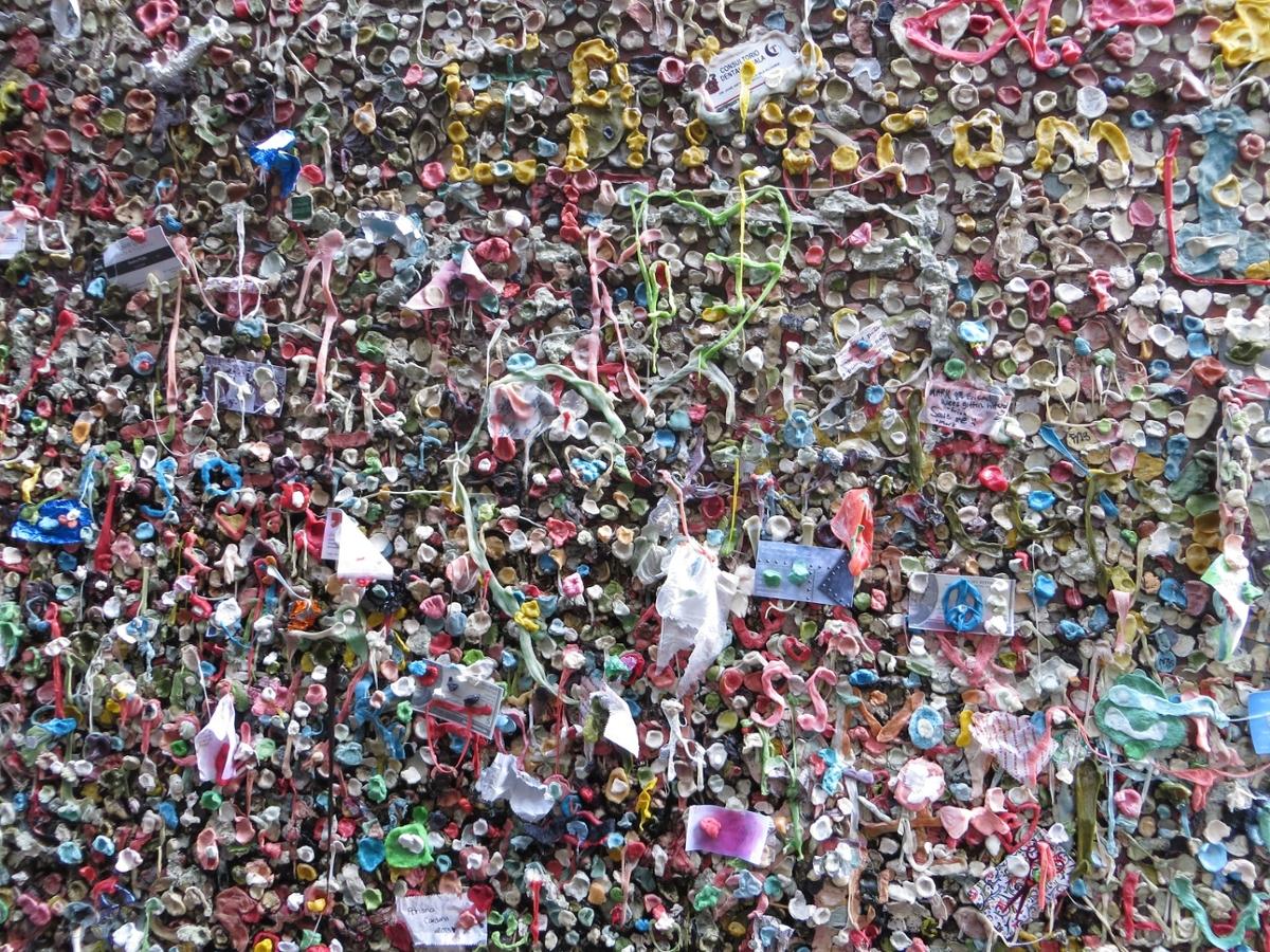 A wall with countless discarded wads of chewing gum stuck to its surface, including other random objects stuck as well