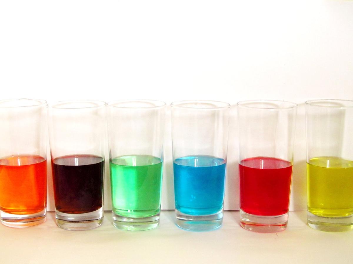 A colorful line of glasses halfway filled with liquid