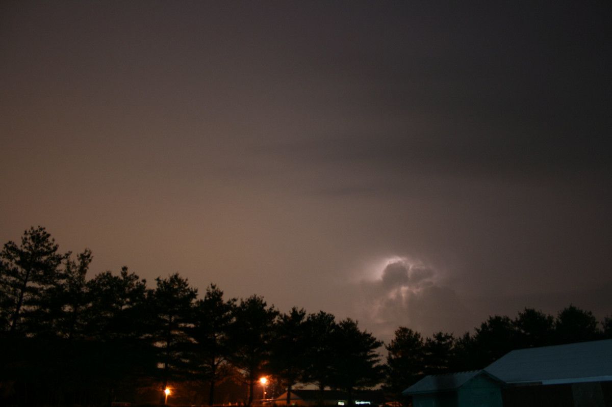 A flash of heat lightning behind a cloud in the night sky