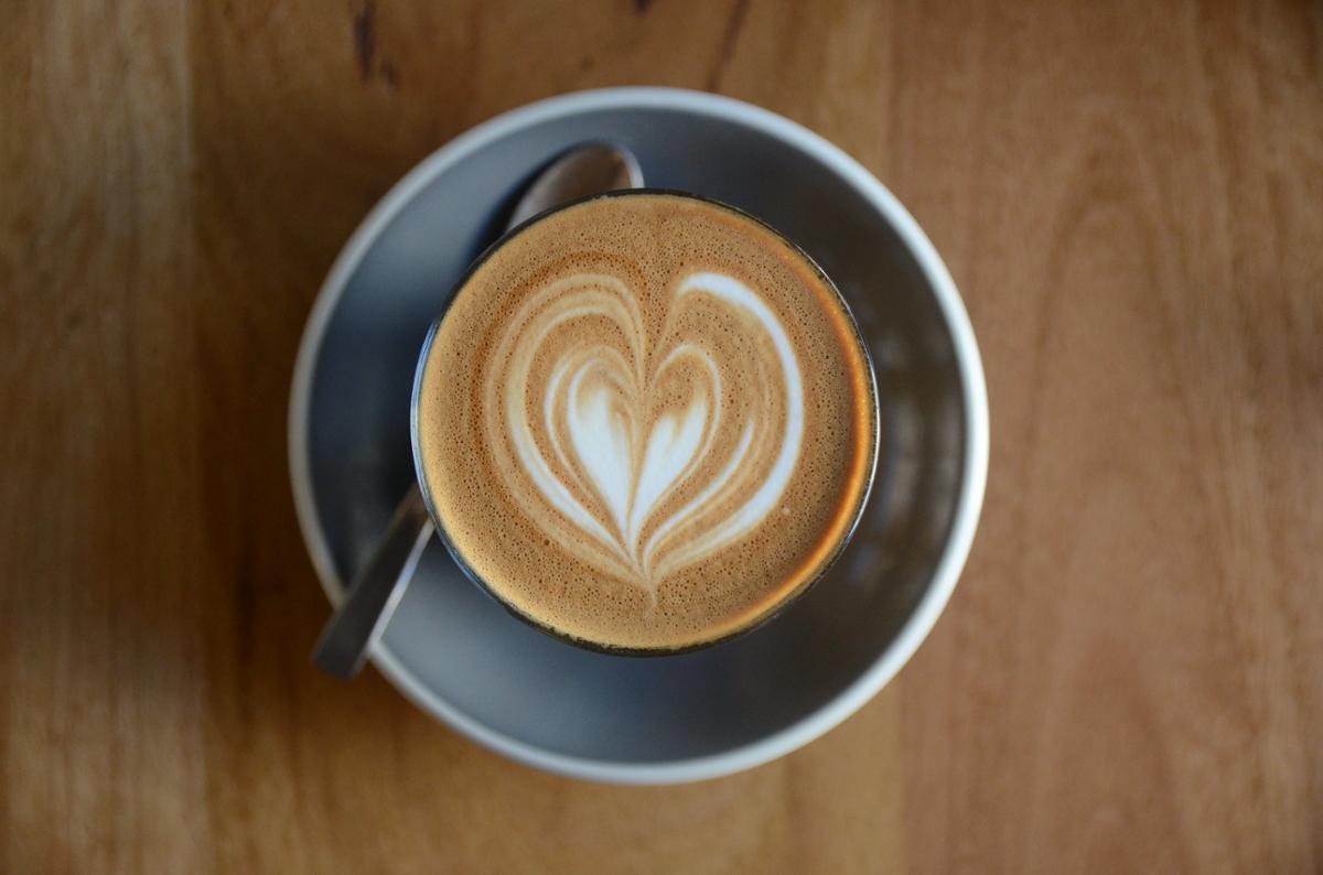 A latte with a heart made from pouring milk viewed from above on a wooden surface