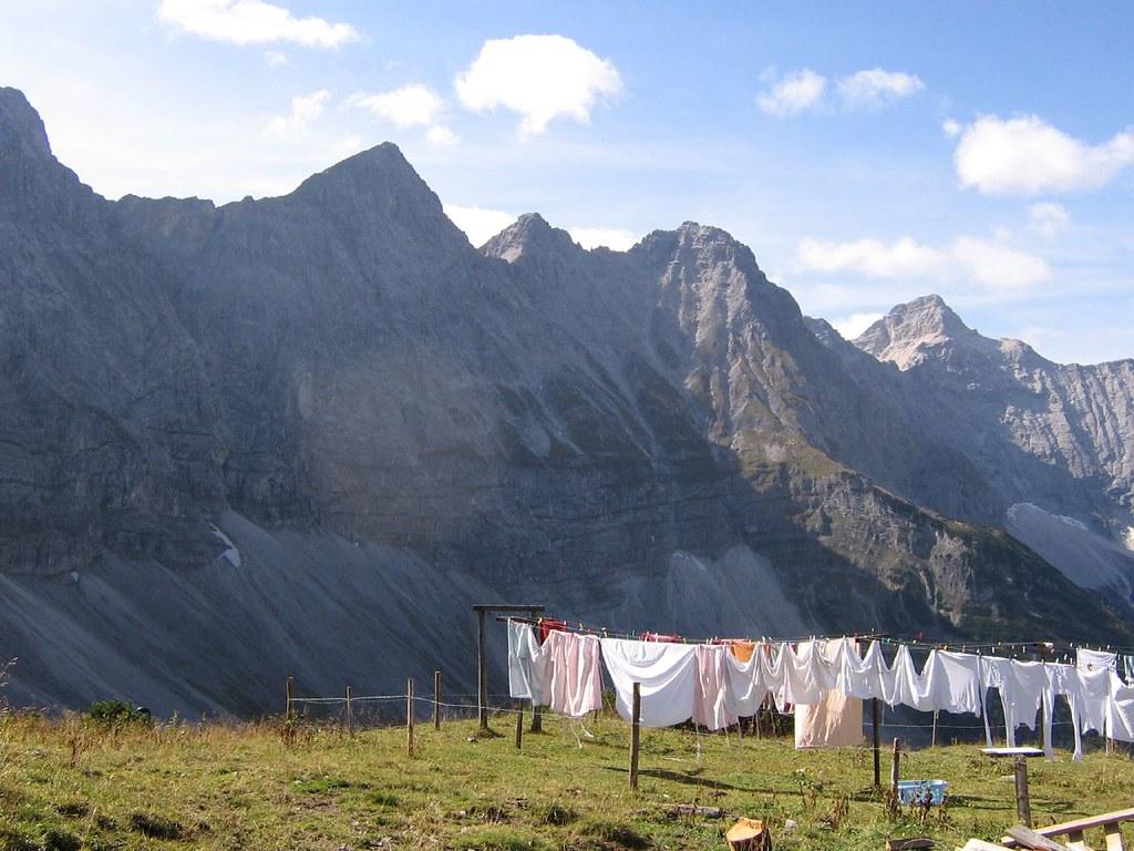 Laundry hangs on a line outside to dry in the sun against a mountainside on a very bright day