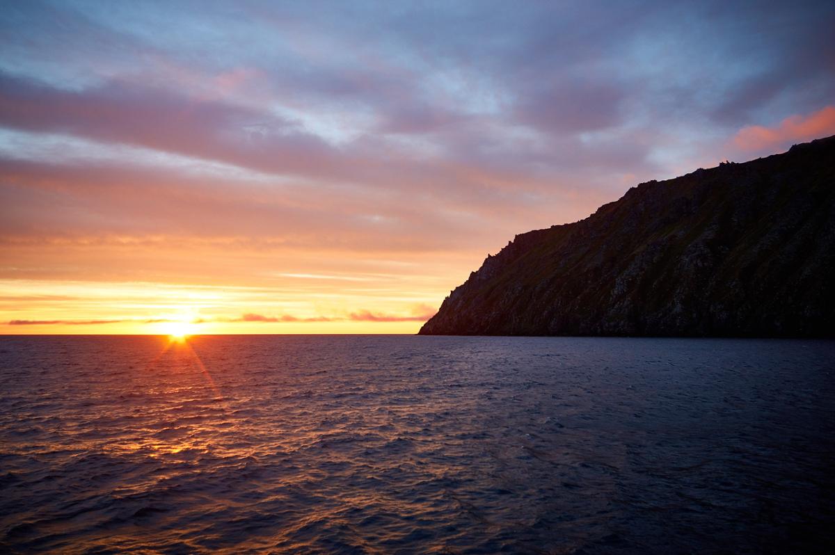 Sunrise on the water near Little Diomede, with the island rising from the water to the right