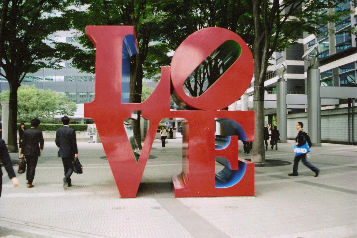 The well-known sculpture of the word "love" in red outside with people walking by
