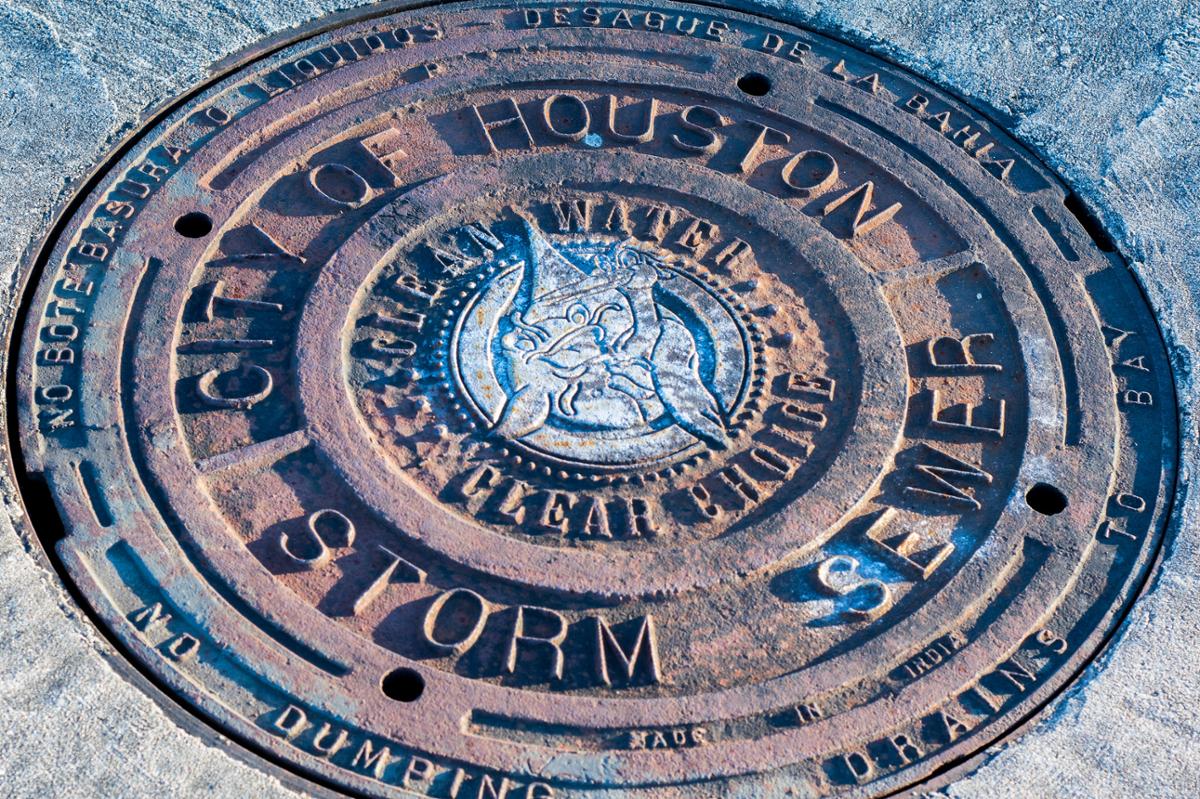 A manhole cover in the street belonging to the city of Houston