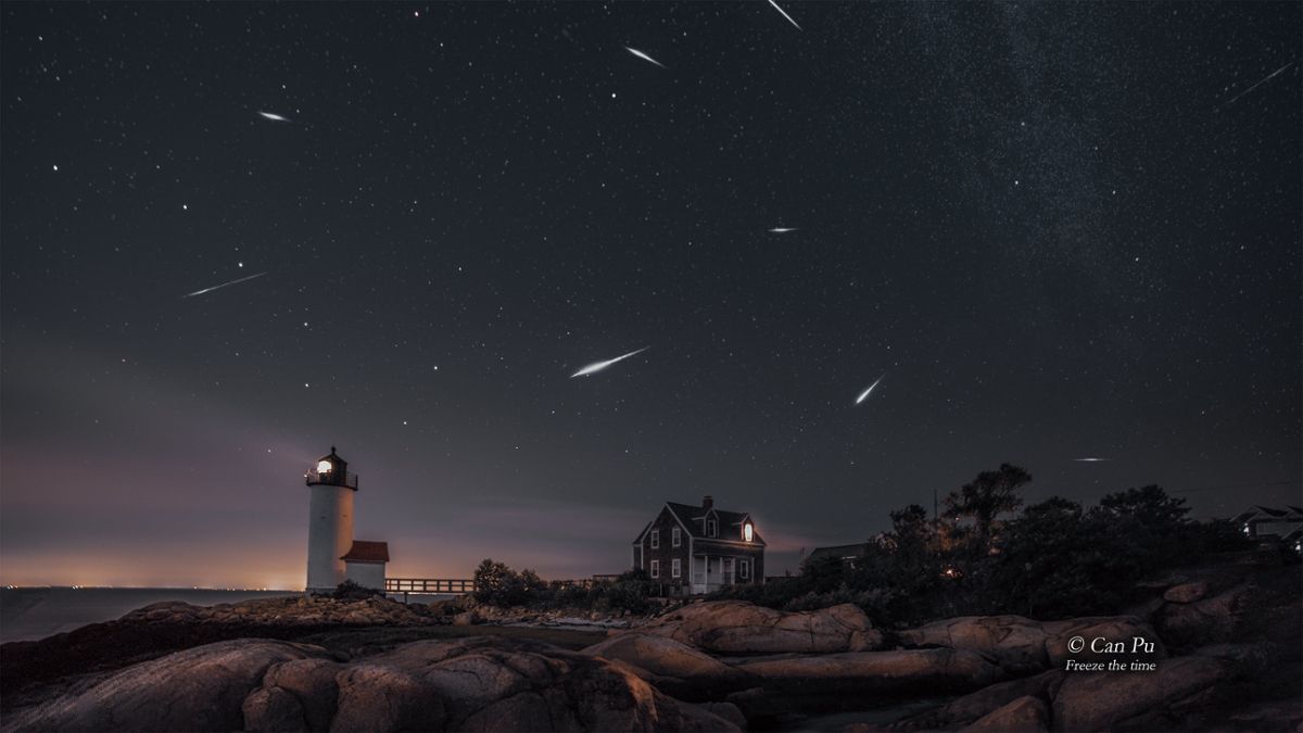 A meteor shower over a lighthouse on a beach at night