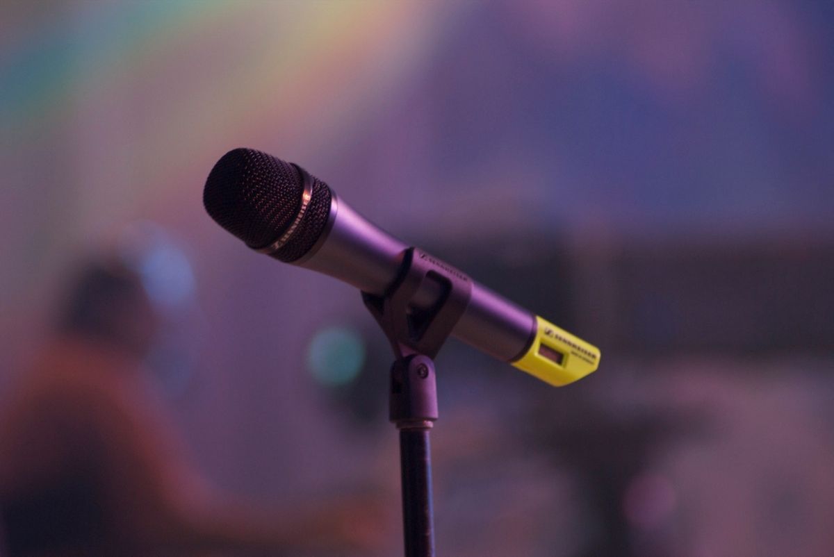 A microphone on a stand in front of a purple background