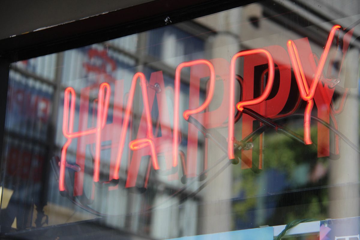 A red neon sign in a window that says "happy"
