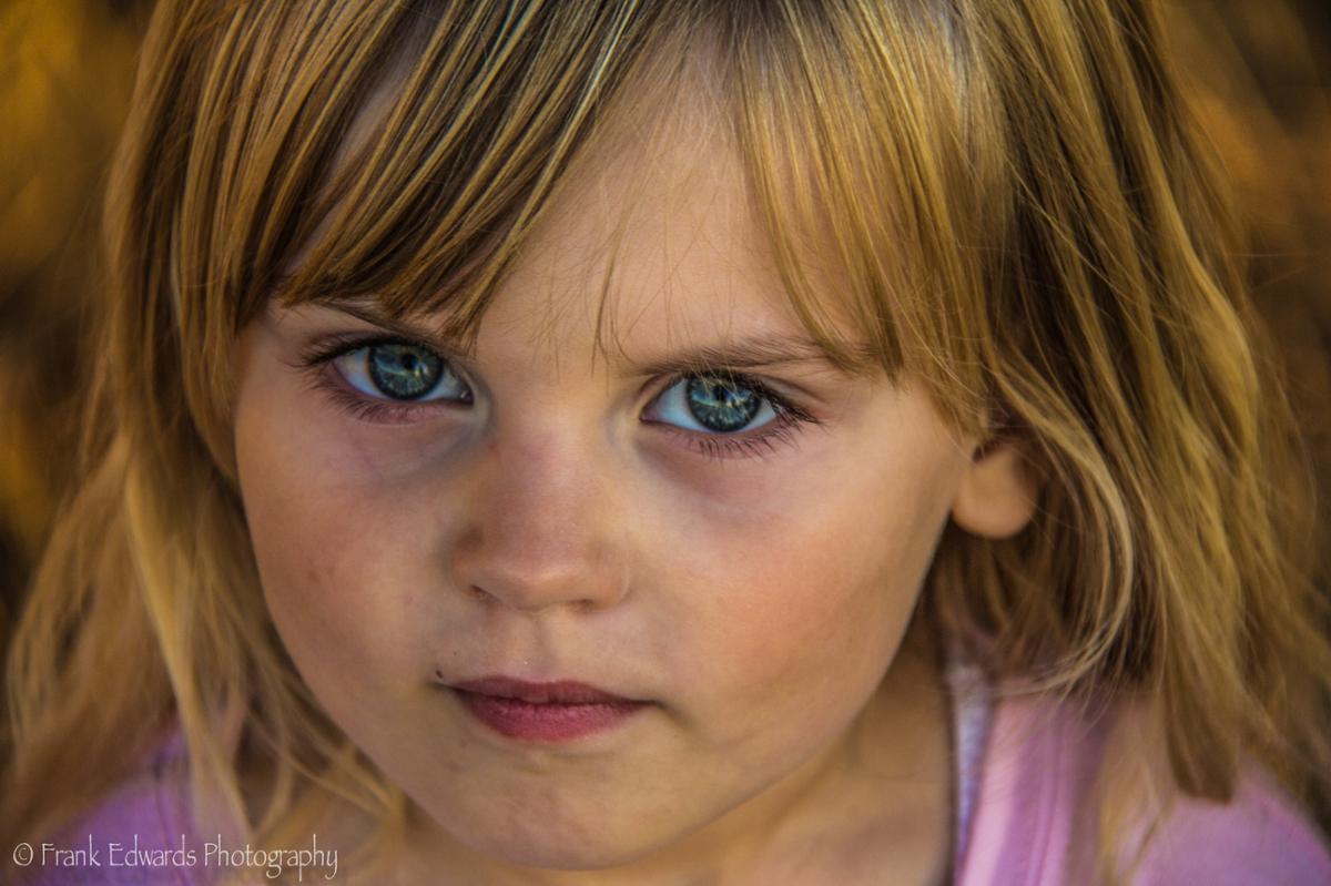 A child with a neutral expression looks into the camera