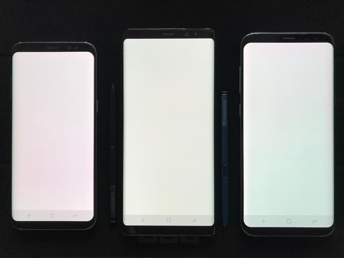 Three smart phones with bright white screens against a dark background