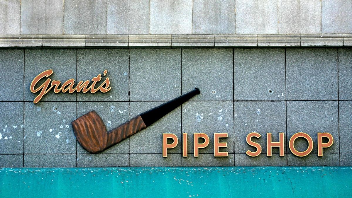 Lettering spelling out "Grant's Pipe Shop" on the side of a stone wall