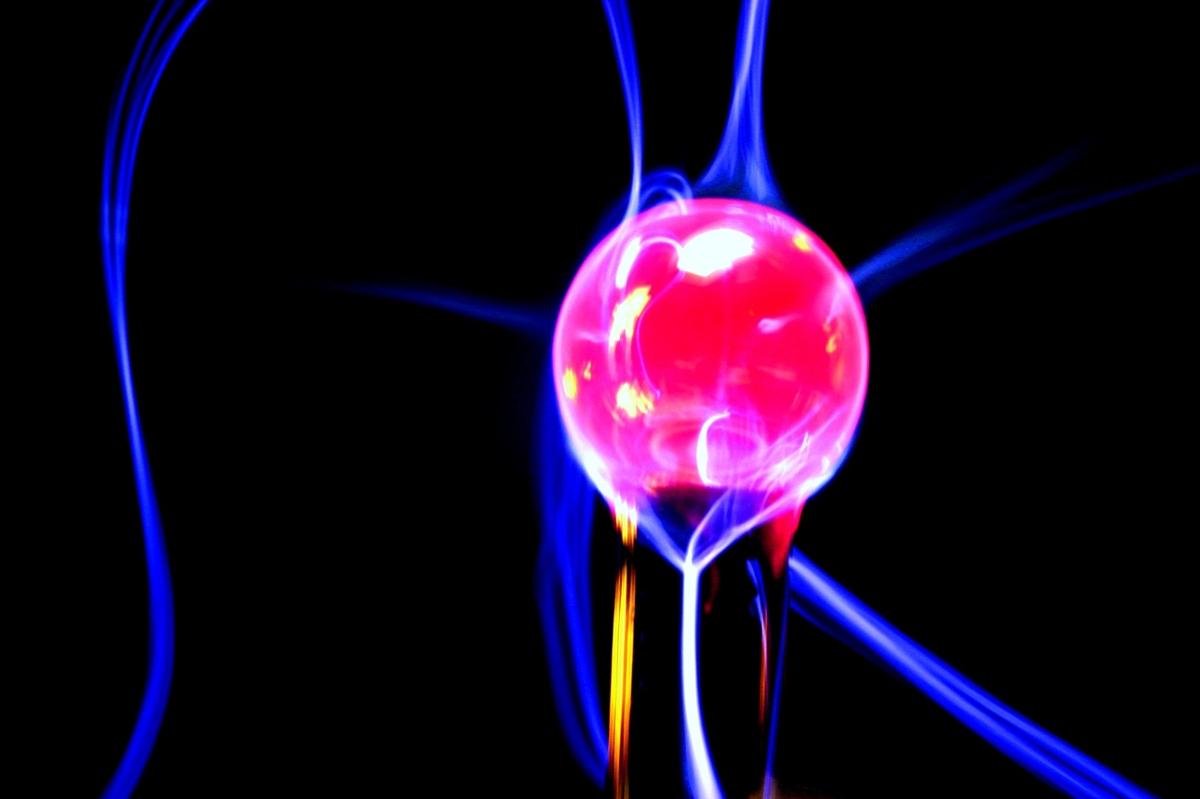 A purple plasma ball with blue tendrils against a black background