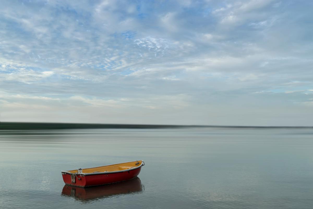 A red rowboat on a calm water surface