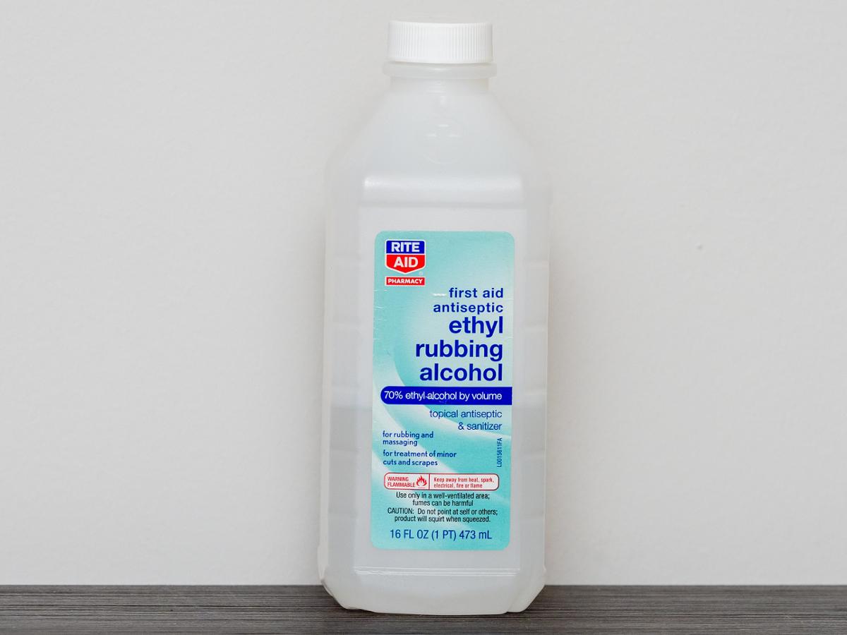 A bottle of rubbing alcohol sits against a blank white wall