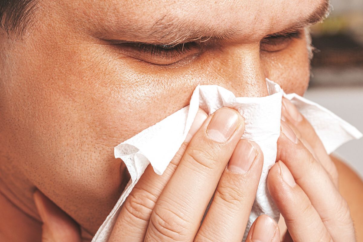 A man blows his nose into a tissue